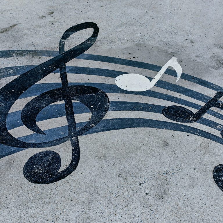 Schwarze und weiße Musiknoten auf einem grauen Untergrund.